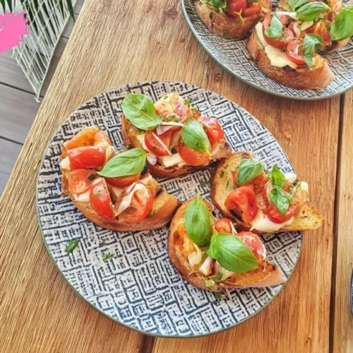 Bruschetta med körsbärstomater och färsk basilika på en träskärbräda