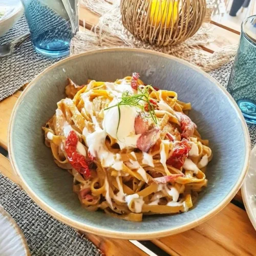 Kall pasta med soltorkade tomater och mozzarella serverad i en tallrik