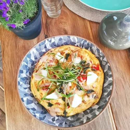 Örtomelett med getost på en tallrik, garnityr av färska örter