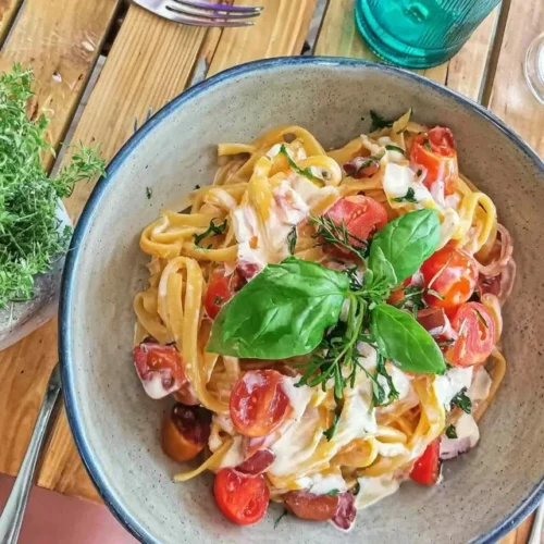 Pasta med tomatsås och färsk basilika på en tallrik.