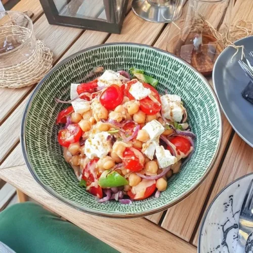 Sallad med rostade kikärtor, tomater och fetaost på en tallrik.